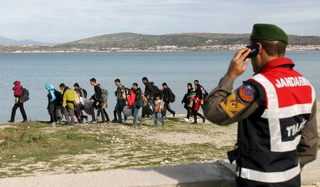 Ein türkischer Polizist überwacht Flüchtlinge, die nahe nahe der...