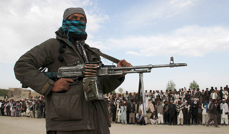 Ein Taliban-Kämpfer bei der öffentlichen Hinrichtung von drei mu... Ein Taliban-Kämpfer bei der öffentlichen Hinrichtung von drei mu...