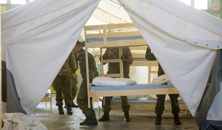 Soldaten beim Einrichten von Schlafzelten auf dem Gelände des eh...