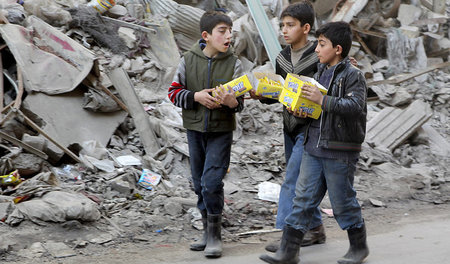 Kurze Pause vom Krieg: Drei Jungen laufen am 2. März mit Kekspac...