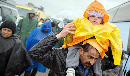 Flüchtling trägt ein schlafendes Kind am 13.März in Idomeni an d...