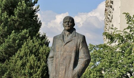 Lenin, breitschultrig im Mantel, schaut nach den Arbeitern des I...