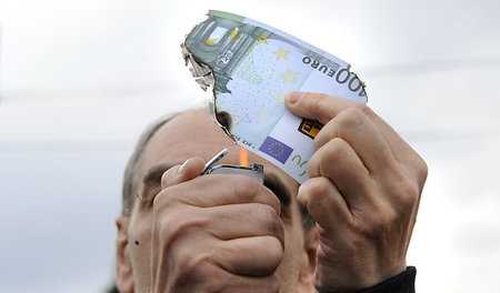 Kein Euro den Gläubigern: Ein Demonstrant verbrennt eine 100-Eur...