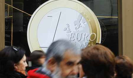 Entlang am Symbol eines Euros schlendern die Menschen in Madrid ...