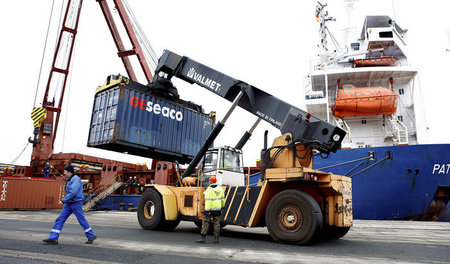 Gefährdeter Beruf: Hafenarbeiter beim Verladen von Containern in...