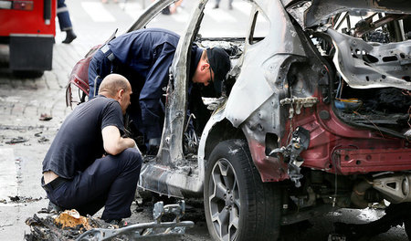Nach dem Attentat untersuchen Polizisten die Trümmer des Autos, ... Nach dem Attentat untersuchen Polizisten die Trümmer des Autos, ...