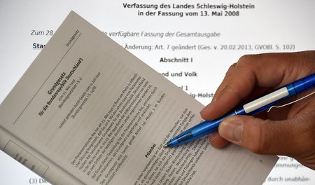 Ein Mann zeigt auf das Wort Gott in der Präambel des Grundgesetz...