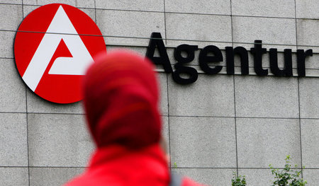 Eine Frau geht an der Agentur für Arbeit vorbei. Bezieht sie Har... Eine Frau geht an der Agentur für Arbeit vorbei. Bezieht sie Har...