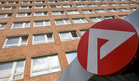 Das Logo der Agentur für Arbeit hängt in Hamburg über einem Agen...
