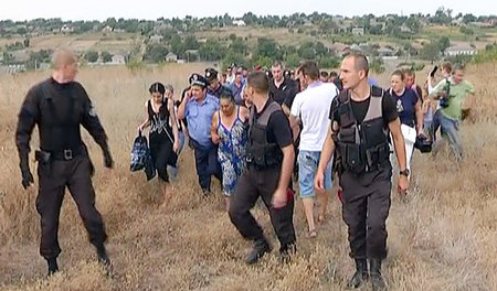 Koordinierte Vertreibung: Polizisten eskortieren eine Gruppe fli...