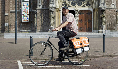 Ein Briefträger der PostNL radelt durch das niederländische Städ...