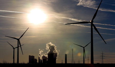 Umstrittene Koexistenz: Sonnenschein über Windturbinen und dem R... Umstrittene Koexistenz: Sonnenschein über Windturbinen und dem R...