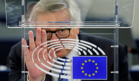 Der EU-Kommissionspräsident Jean-Claude Juncker sitzt hinter ein...