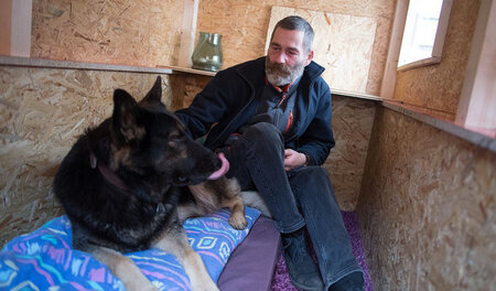 Ein Obdachloser und sein Hund in einer Wohnbox in Köln, die der ... Ein Obdachloser und sein Hund in einer Wohnbox in Köln, die der ...