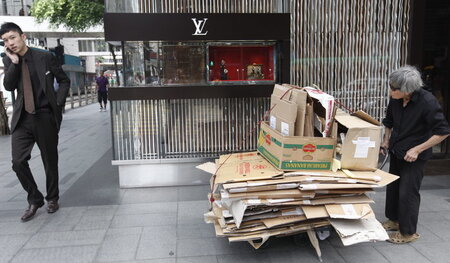 Hongkong, 19. Juni 2012: Vor einer Luxusboutique schiebt ein Man... Hongkong, 19. Juni 2012: Vor einer Luxusboutique schiebt ein Man...