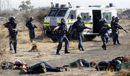 Polizeitruppen und deren Opfer am 16. August nahe der Marikana-P... Polizeitruppen und deren Opfer am 16. August nahe der Marikana-P...