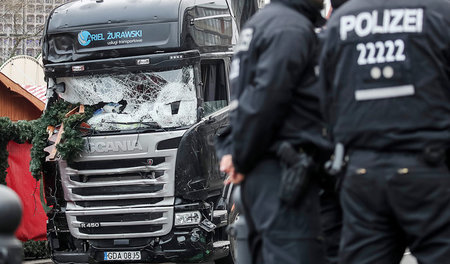 Polizisten vor dem zerstörten Tat-Lkw am 20.Dezember auf dem Wei...