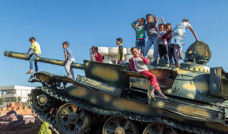 Kinder spielen auf Panzern, die Teil eines Denkmals für die gefa...