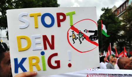 Ein Junge hält ein Plakat mit der Aufschrift »Stoppt den Krieg« ...