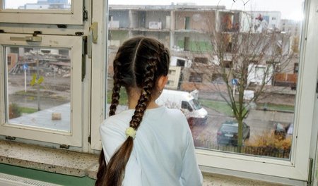 Ein Schulmädchen schaut aus dem Fenster im Kinder- und Jugendpro...