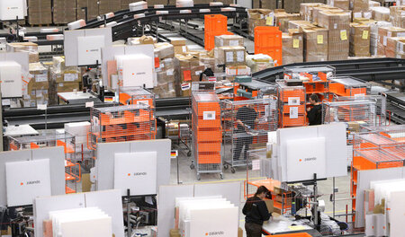 Schuften für einen niedrigen Lohn: Mitarbeiter verpacken Ware in... Schuften für einen niedrigen Lohn: Mitarbeiter verpacken Ware in...