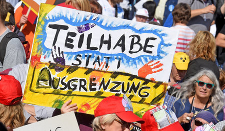 Mit Plakaten versammeln sich tausende Menschen mit Behinderung a...