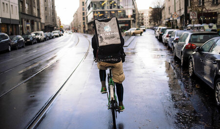 Ein Fahrradkurier des Lieferdiensts Deliveroo ist auf einer nass...