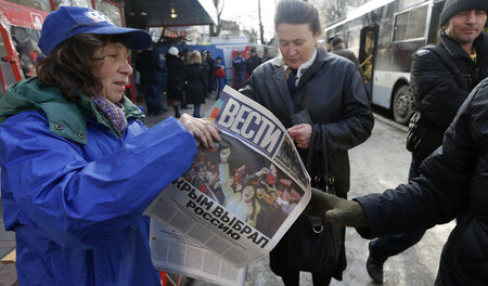 Eine Frau mit einer Ausgabe der Tageszeitung Westi in der Stadt ...