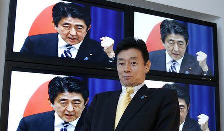 Der LDP-Politiker Yasutoshi Nishimura sitzt vor einer Wand aus B...