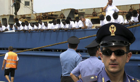 Ein italienischer Polizist bewacht ein deutsches Schiff, das afr... Ein italienischer Polizist bewacht ein deutsches Schiff, das afr...