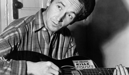 Man achte auf den Aufkleber an Woody Guthries Gitarre